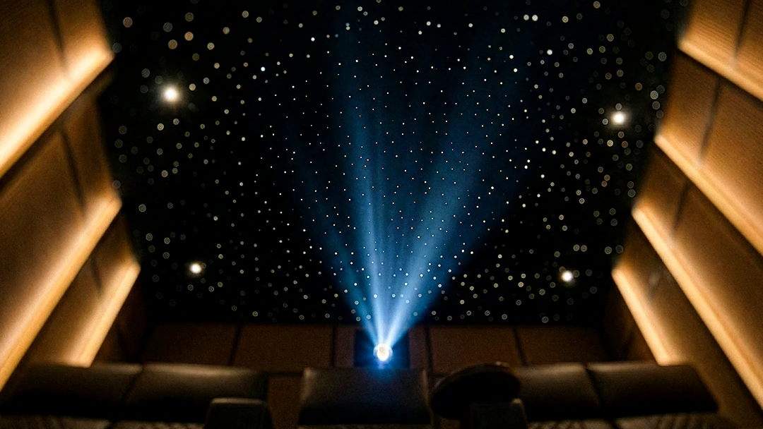 Luxury home theater in Theater 2014 featuring a fiber optic star ceiling, projector beam, and warm architectural wall lighting.